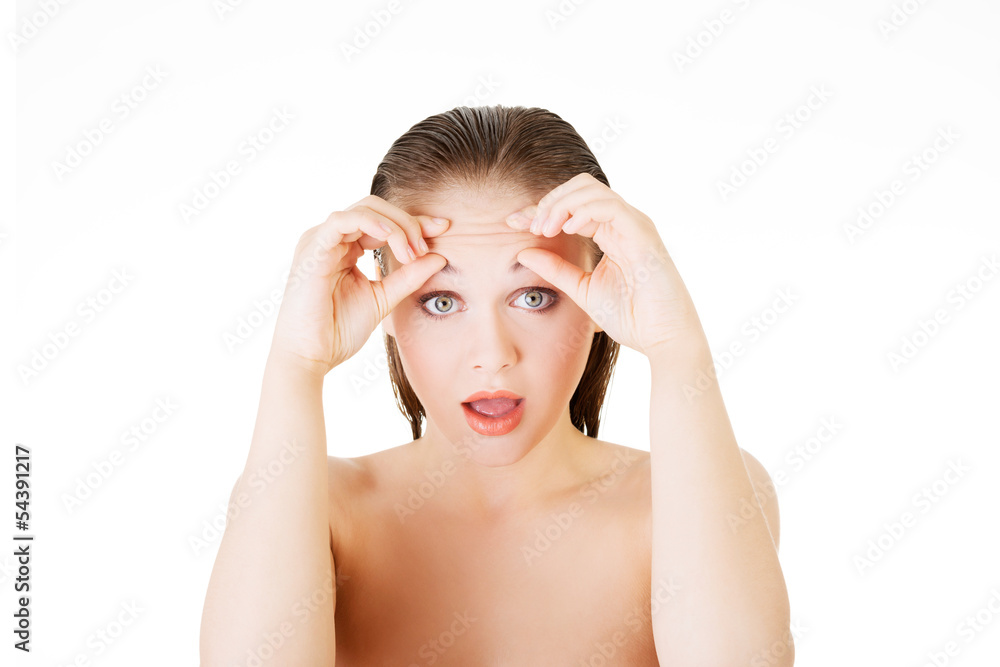 Woman checking her wrinkles on her forehead Woman checking her wrinkles on her forehead