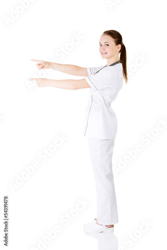 Woman doctor or nurse pointing on copy space.