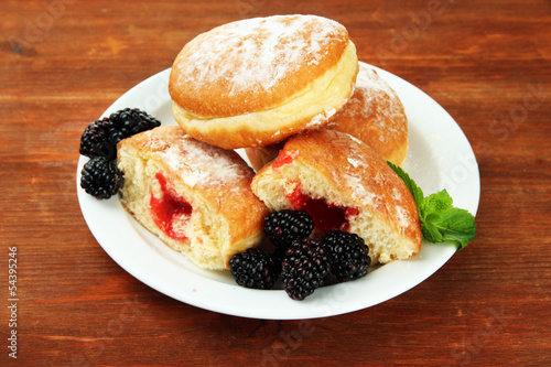 Tasty donuts with berries on wooden table