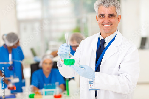 senior scientist holding laboratory glassware