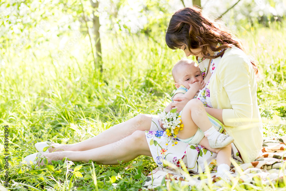 young mother breast feeding her baby outdoors summertime young mother breast feeding her baby outdoors summertime