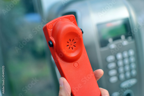 Mano tiene una cornetta rossa di un telefono   pubblico photo