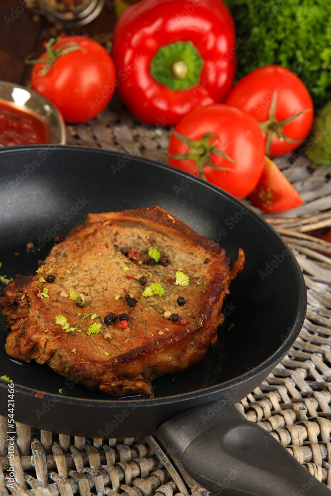 Piece of fried meat on pan on wooden table close-up