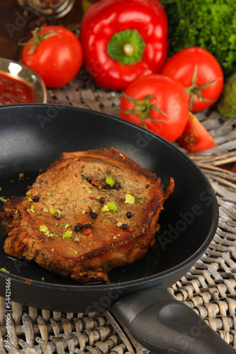 Piece of fried meat on pan on wooden table close-up