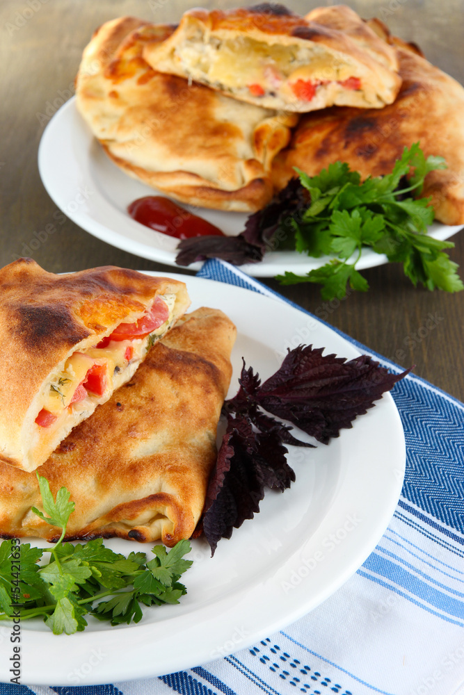 Pizza calzone on plates on napkin on wooden table Pizza calzone on plates on napkin on wooden table