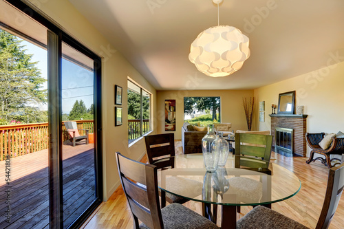Large long living room with dining room table, balcony door.