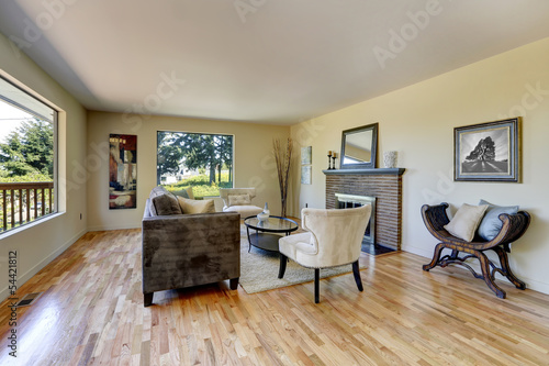 Living room with hardwood floor, fireplace and large windows.