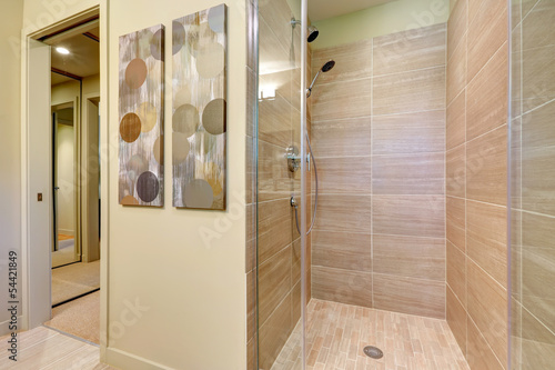 Bathroom shower with glass doors and natural color tiles.