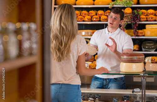 Male salesman in cheese store with a female customer