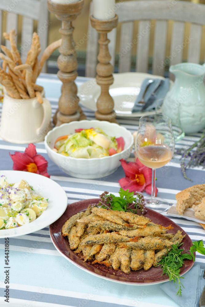 Fried sardines with potato salad, bread and a glass