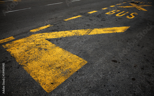 Yellow bus stop marking on dark asphalt road