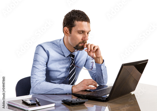thoughtful businessman at office desk looking on laptop