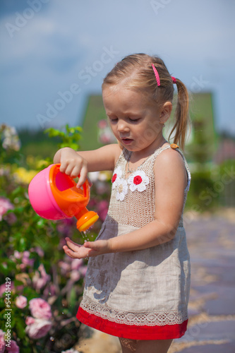 Adorable cute girl watering flowers with a watering can