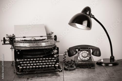 Vintage typewriter, old telephone, retro lamp on table photo