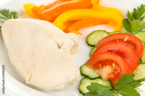 Boiled chicken breast on plate with vegetables close up