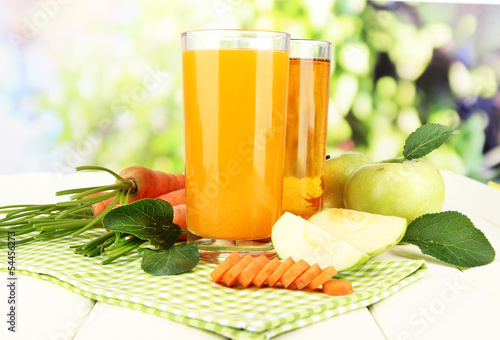 Glasses of juice, apples and carrots