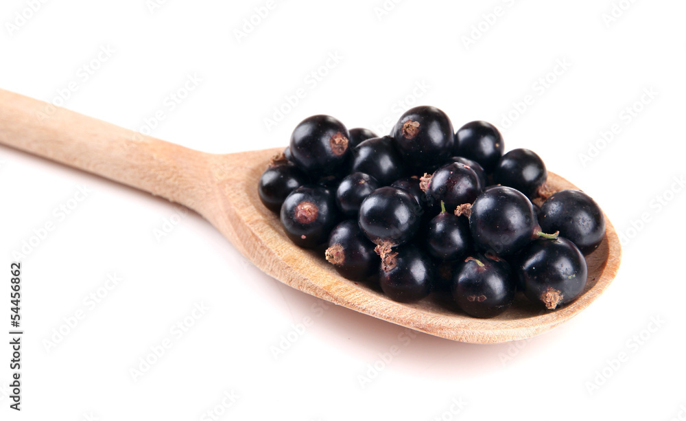 Black currant in wooden spoon isolated on white Black currant in wooden spoon isolated on white