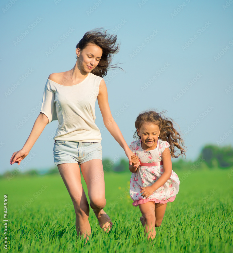 Fototapeta premium Young happy girls running at green wheat field