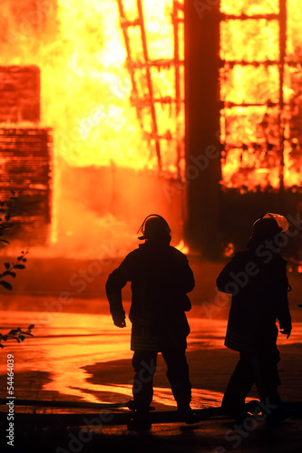 Feuerwehrmänner vor brennender Halle