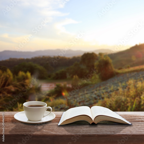 Cup of coffee and a book on a wooden table