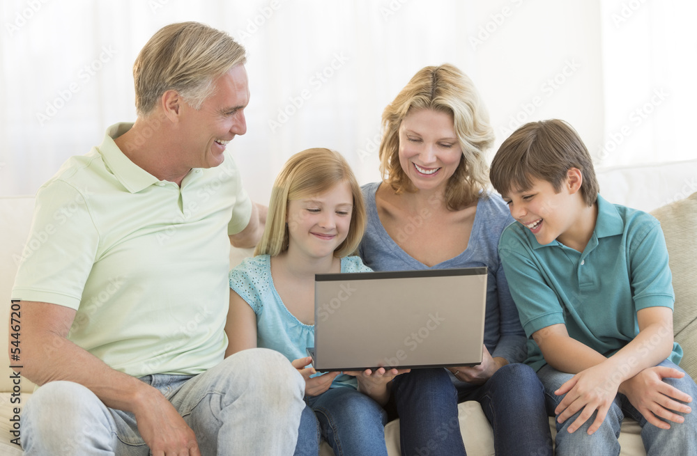 Parents And Children Using Laptop Together On Sofa Parents And Children Using Laptop Together On Sofa