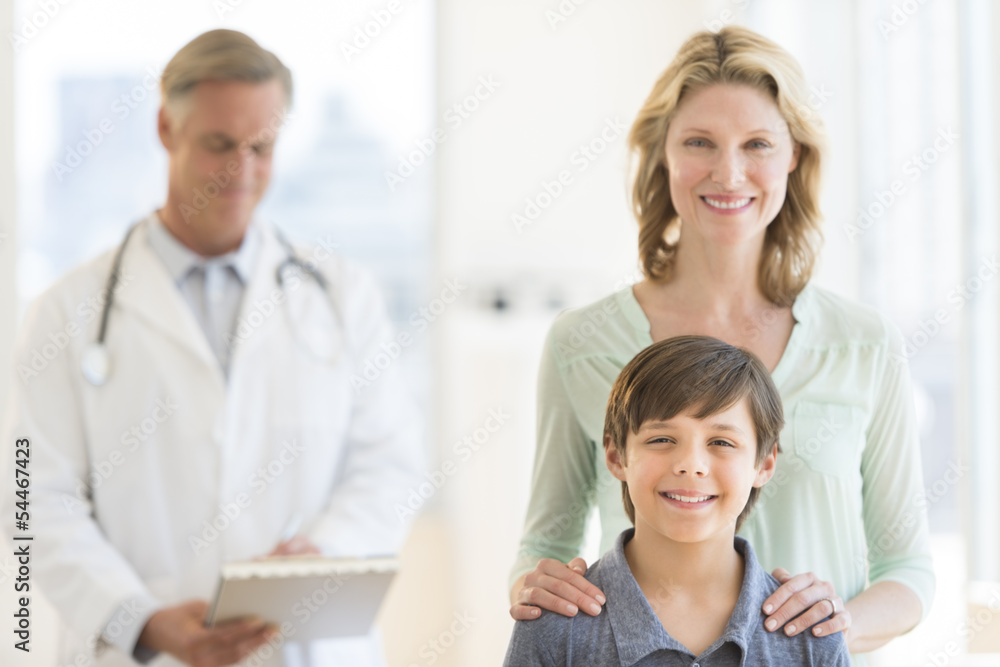 Mother And Son With Doctor Examining Report In Background Mother And Son With Doctor Examining Report In Background