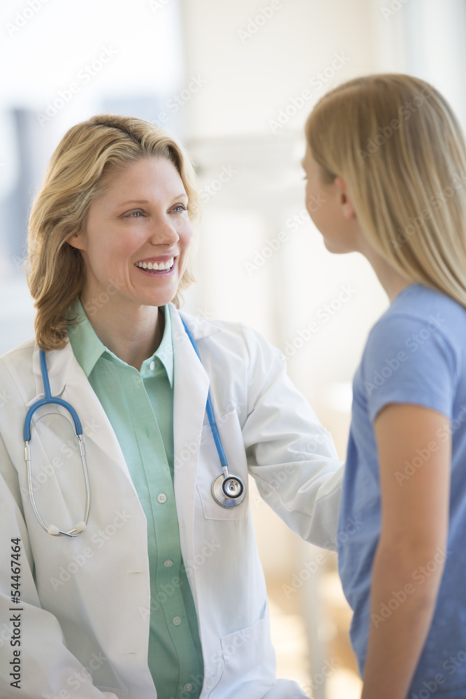Doctor With Stethoscope Around Neck Looking At Girl In Hospital Doctor With Stethoscope Around Neck Looking At Girl In Hospital