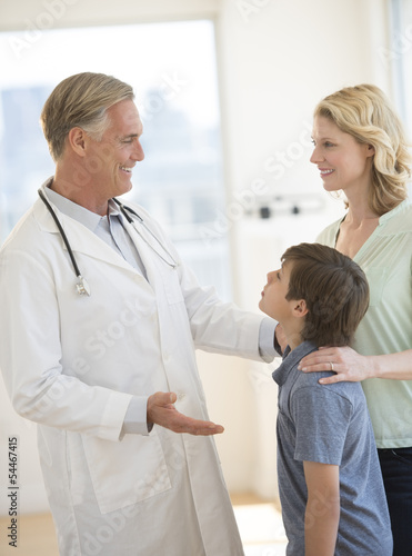 Doctor Explaining Woman About Son's Health In Clinic