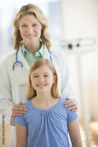 Confident Doctor Standing With Girl In Clinic