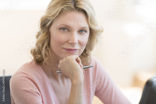 Confident Businesswoman With Hand On Chin In Office