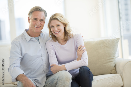 Happy Couple Sitting On Sofa In Living Room