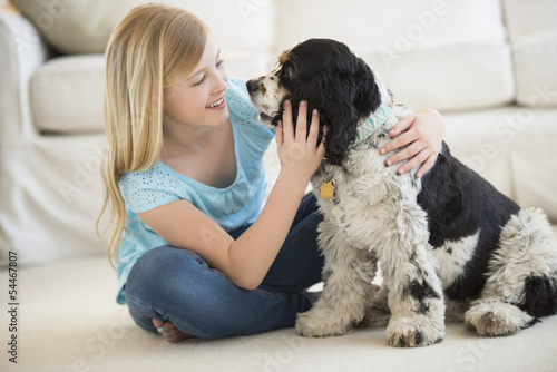 Girl Playing With Pet Dog In Living Room