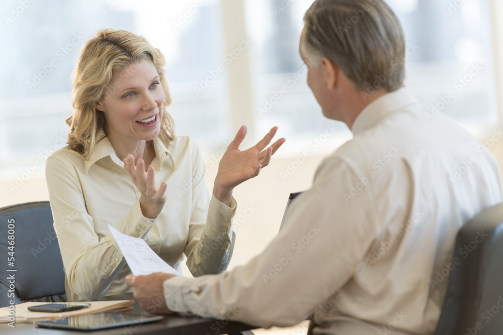 Businesswoman Discussing With Colleague In Office Businesswoman Discussing With Colleague In Office