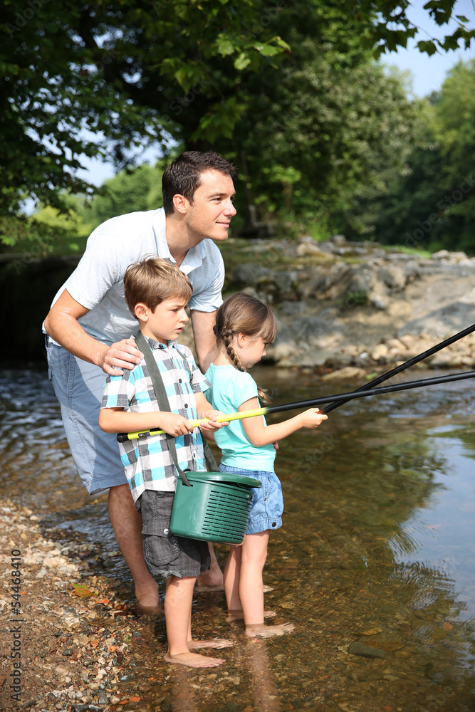 Man teaching kids how to fish in river Man teaching kids how to fish in river