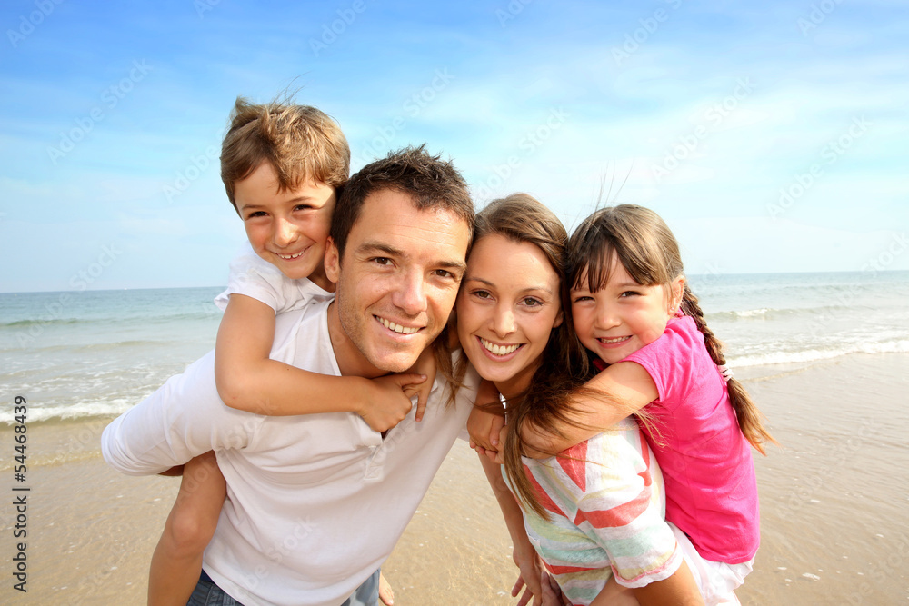 Parents giving piggyback ride to kids at the beach