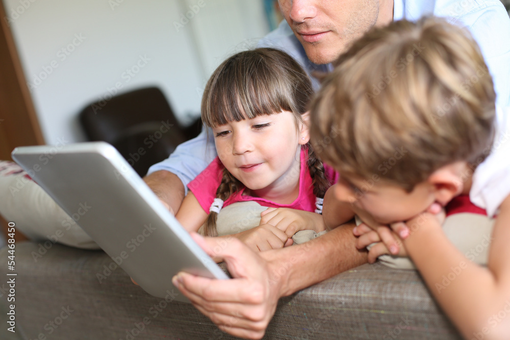 Father and children playing with tablet at home Father and children playing with tablet at home