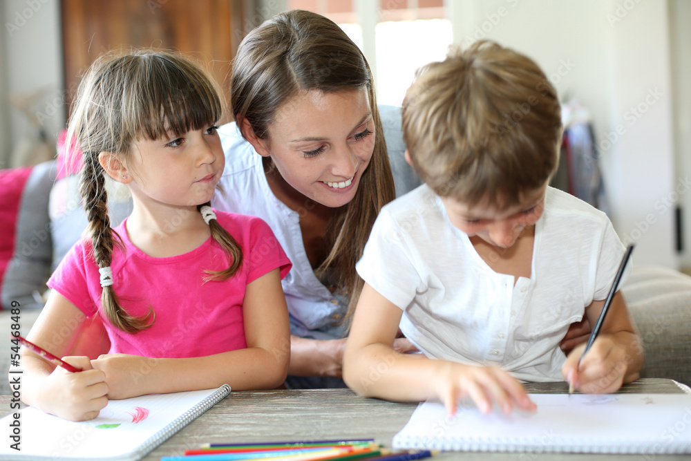 Mother watching kids making drawings at home Mother watching kids making drawings at home