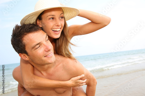 Man giving piggyback ride to girlfriend by the ocean