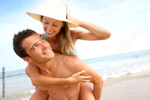 Man giving piggyback ride to girlfriend by the ocean