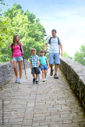 Family on a rambling journey crossing roman bridge