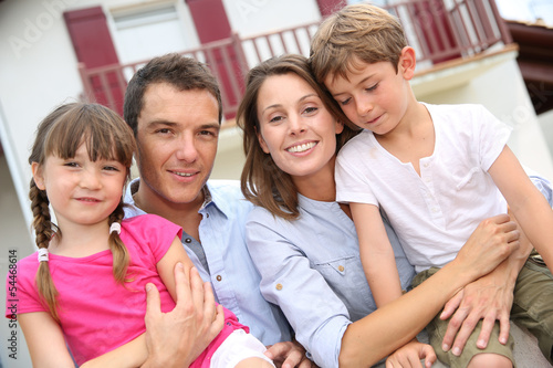 Foto Happy family standing in front of new home