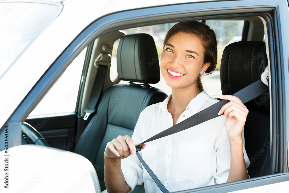 Attractive young woman in a car fastens seat belt