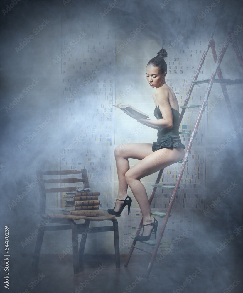 A young woman in lingerie reading a book on the ladder A young woman in lingerie reading a book on the ladder