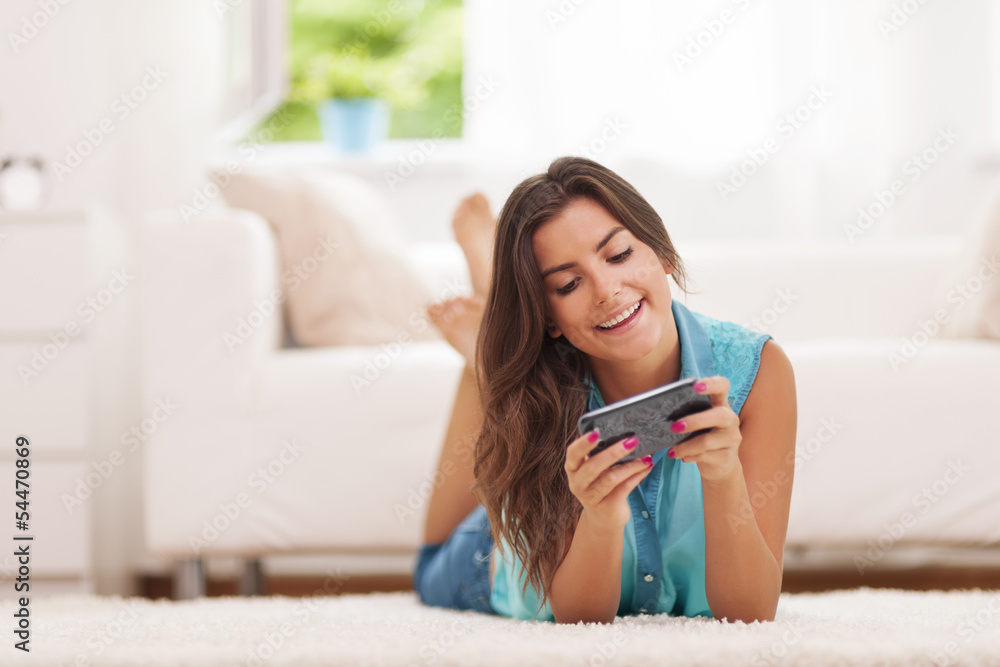 Happy young woman text messaging at home Happy young woman text messaging at home
