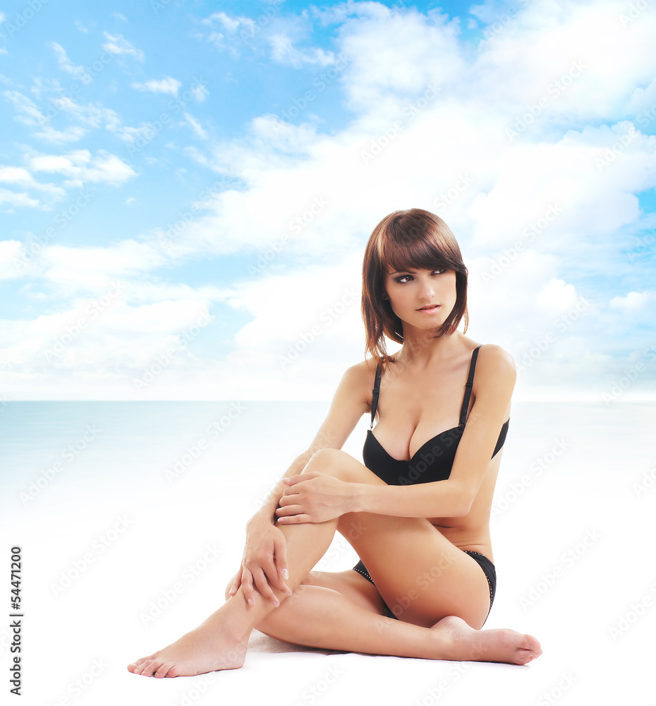A young brunette woman in a swimsuit relaxing on the beach