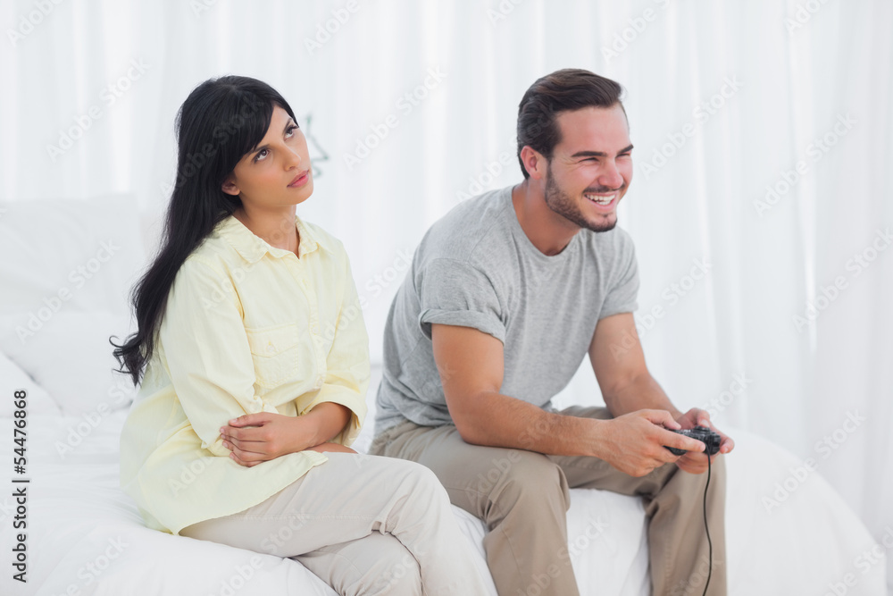 Annoyed woman looking up during her boyfriend playing video game Annoyed woman looking up during her boyfriend playing video game