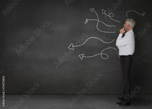 Thoughtful businessman looking at arrows