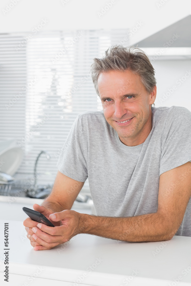 Smiling man texting in kitchen Smiling man texting in kitchen