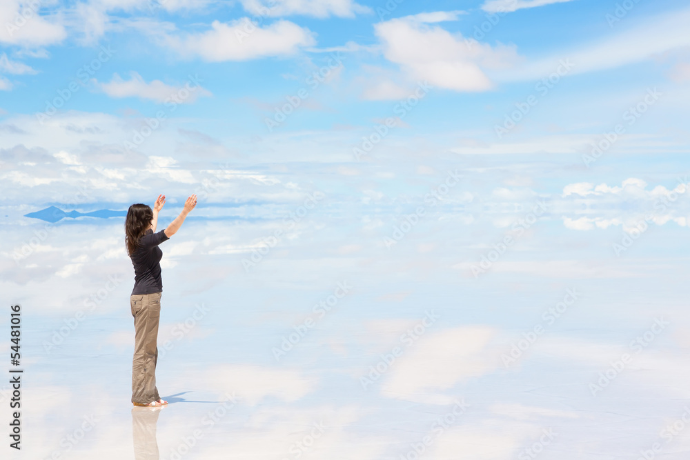 Woman standing on Salar de Uyuni with raised hands Woman standing on Salar de Uyuni with raised hands