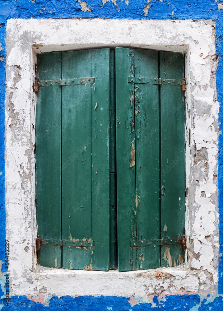 Old rustic window with green shutters.